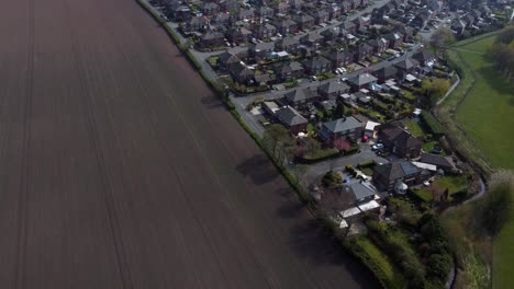 countryside housing estate aerial view flying above england plowed farmland residential community homes