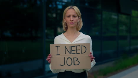 woman holding cardboard sign seeking employment