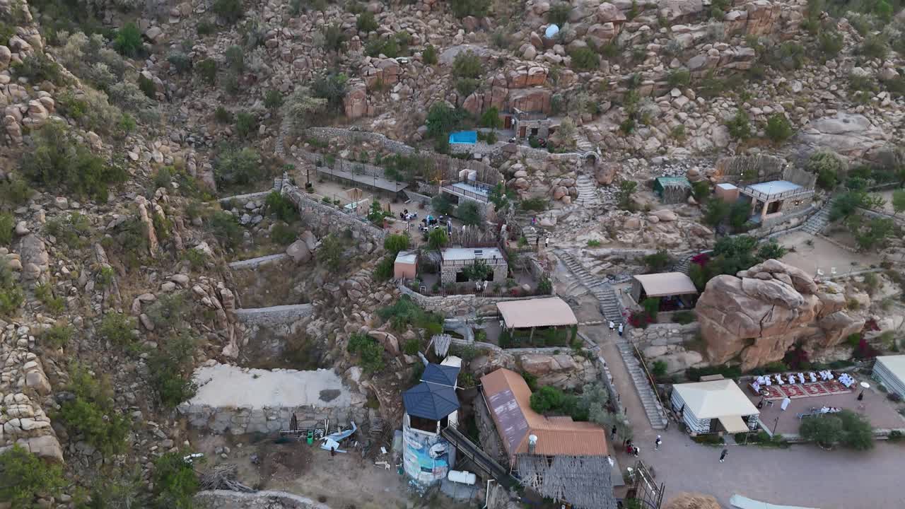 Aerial view tilting over a hillside town, sunny evening in Taif, Saudi Arabia
