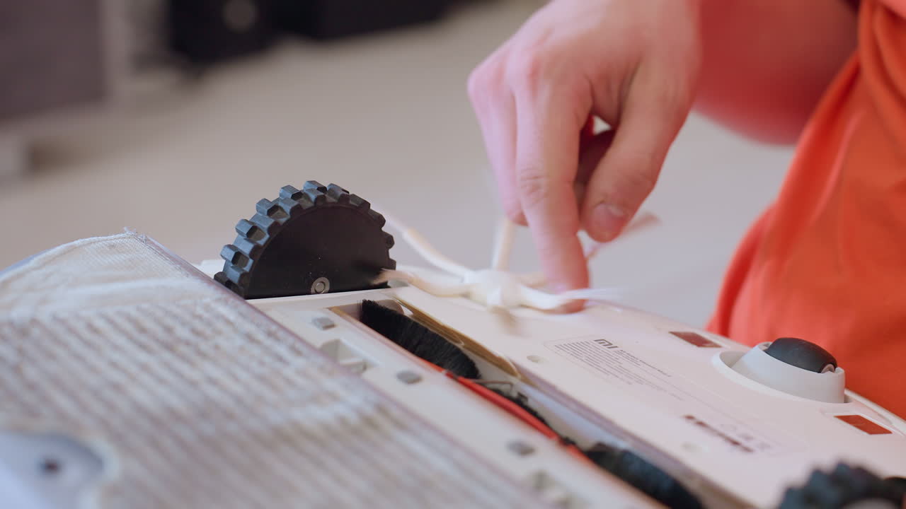 Close up of hand adjusting side brush on robot vacuum during maintenance process showing detailed care for household cleaning device to ensure proper function and performance on home floors