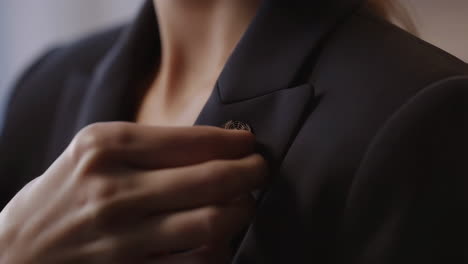 close-up of a hand fastening a pin on a blazer lapel