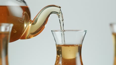 pouring tea from a teapot into a glass