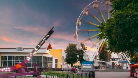 rotating in natural motion effect illuminated attraction ferris wheel on summer evening in city amusement park