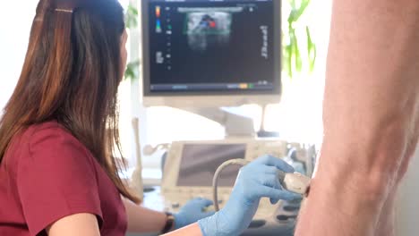 female doctor performs ultrasound examination with probe on woman abdomen near monitor. routine medical check-up and diagnostic procedure in clinic