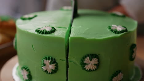 cutting a green frosted cake