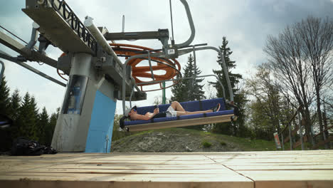 lone guy leisurely resting on a ski lift during summertime