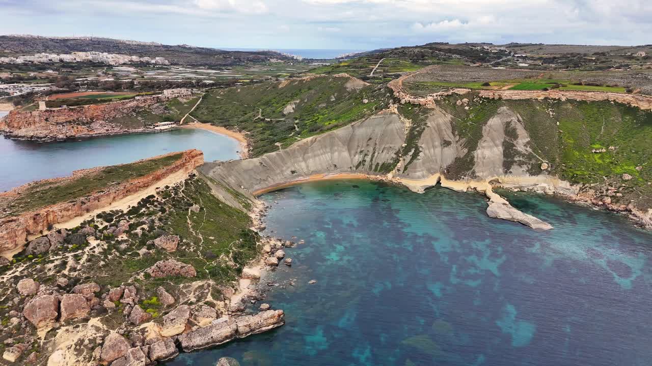 Drönarvy över Qarraba Bay på Malta som visar branta kalkstensklippor, klippig kustlinje och små turkosa vikar längs ett klart, lugnt hav i mjukt dagsljus