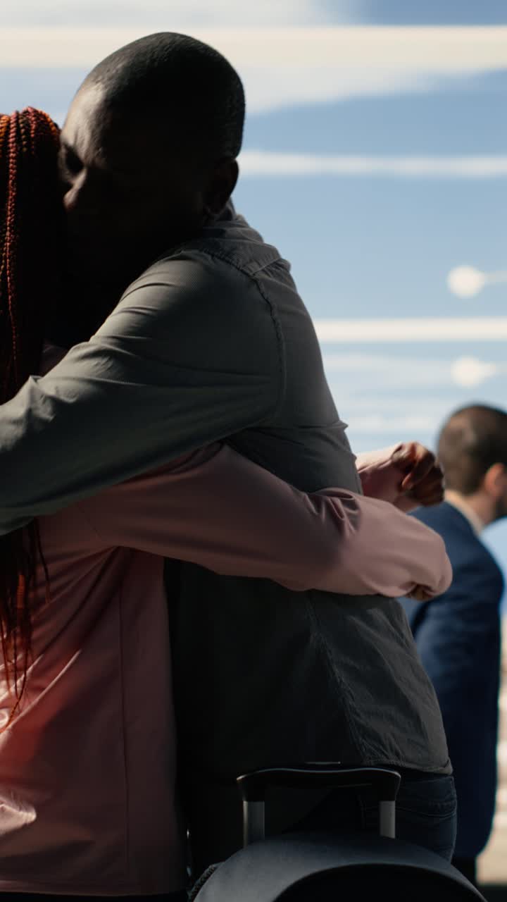 African American Couple Hugging at Airport with Suitcase