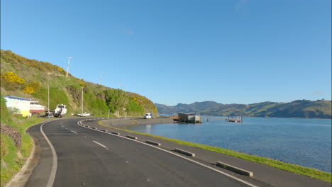 Punto-De-Vista-Del-Coche-Conduciendo-Por-La-Carretera-Costera-A-Lo-Largo-Del-Mar-Azul-En-La-Península-De-Dunedin,-Otago,-Nueva-Zelanda