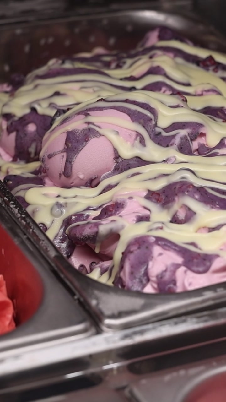 Palline di gelato ai frutti di bosco rosa irrorate con salsa al cioccolato bianco