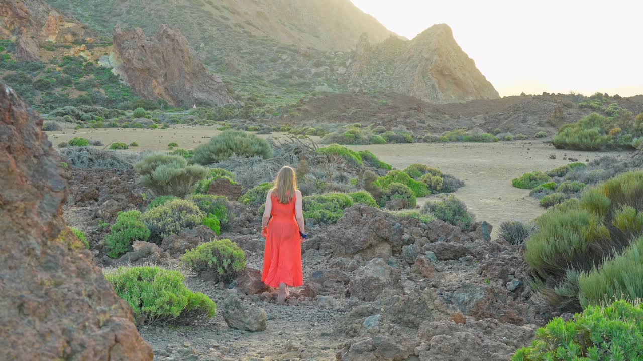 빨간 옷을 입은 여자가 테이데 국립공원을 탐험합니다. 화성과 같은 풍경입니다.