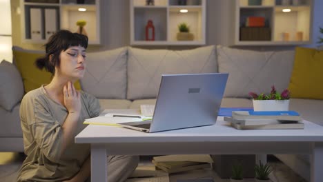 젊은 여성이 밤에 컴퓨터를 사용하면서 피곤해집니다.