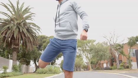 jogging outdoors, man in hoodie and shorts exercising on suburban street