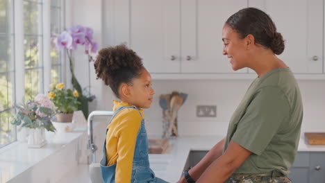 Madre-Del-Ejército-Americano-En-Casa-Uniforme-De-Licencia-Jugando-Con-Su-Hija-En-La-Cocina-Familiar