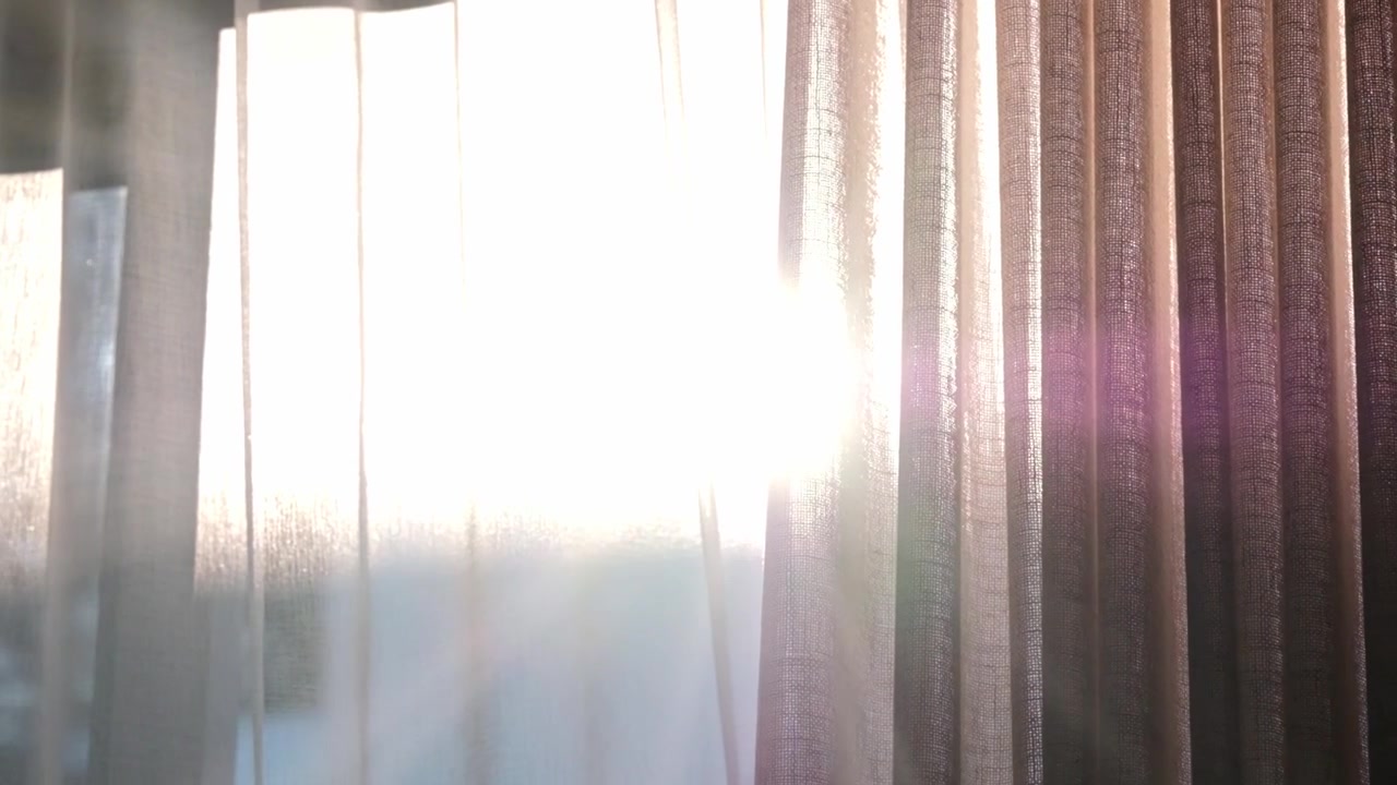 The sun shines through fabric curtains in a dreamy way