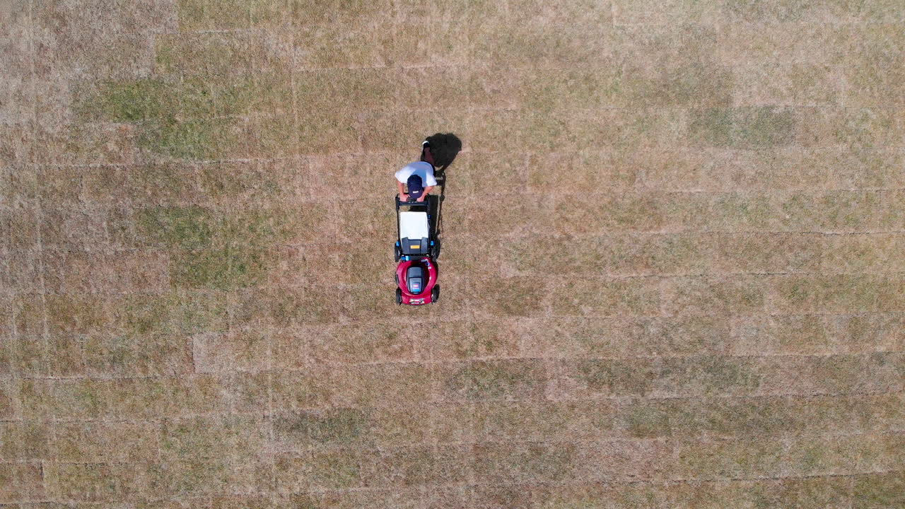 Hombre cortando el césped con dron en ángulo descendente