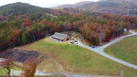 a wide orbiting drone shot of a barn in the mountains during fall in sunset south carolina