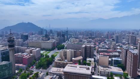 pan drone shot of santiago cityscape featuring entel tower, la moneda palace, and the andes mountains in the background