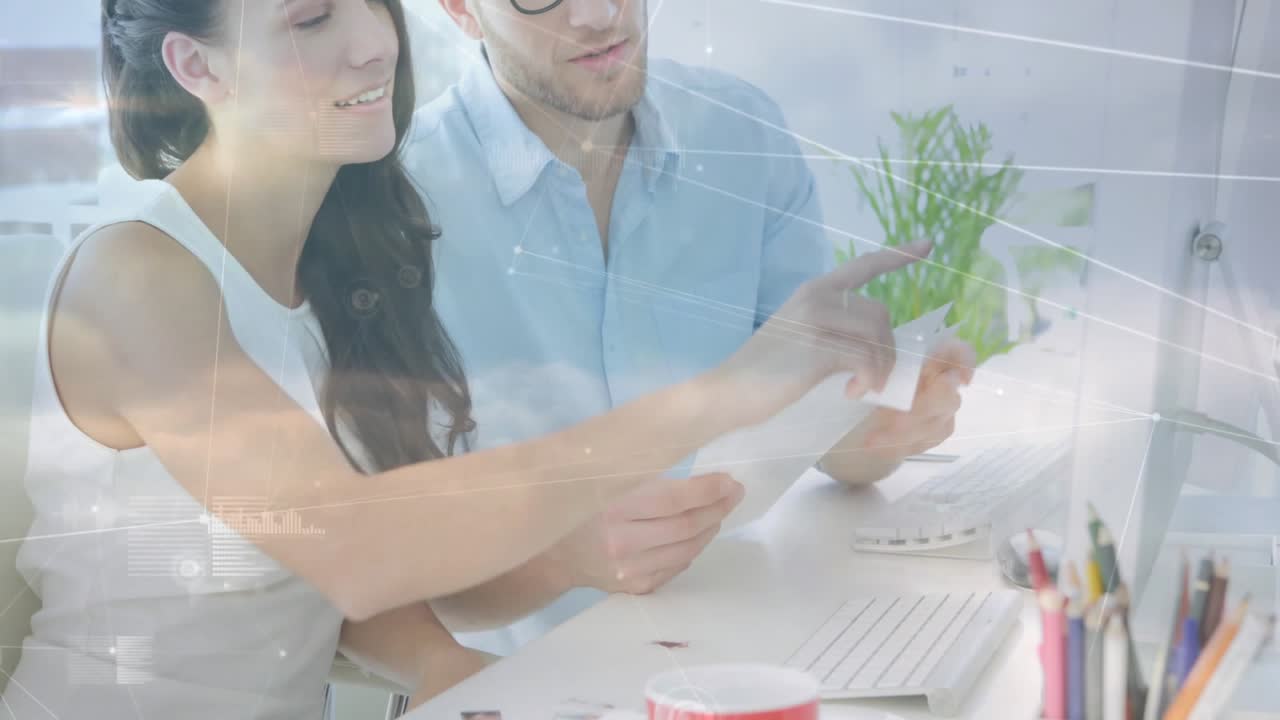 Donna che prende un documento stampato e guida un uomo verso lo schermo del computer, concludendo la revisione del progetto.