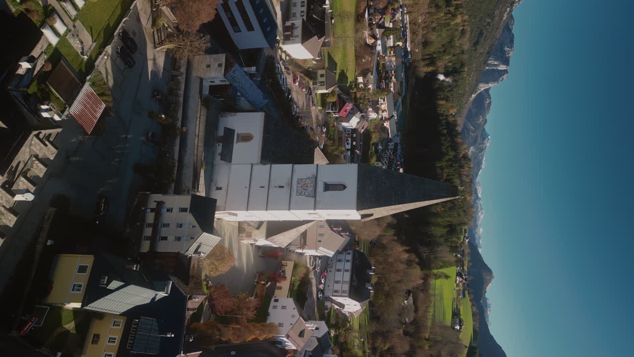 Aerial view of a town with a church and mountains