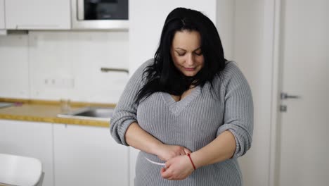 mujer hermosa sintiéndose feliz después de medir su cintura en casa
