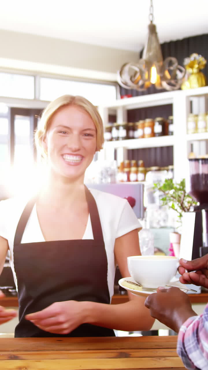 Smiling waitress serving cup of coffee to customer