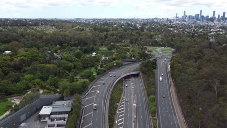 aerial view of a major highway with roundabout and a tunnel entrance city skyline in the background