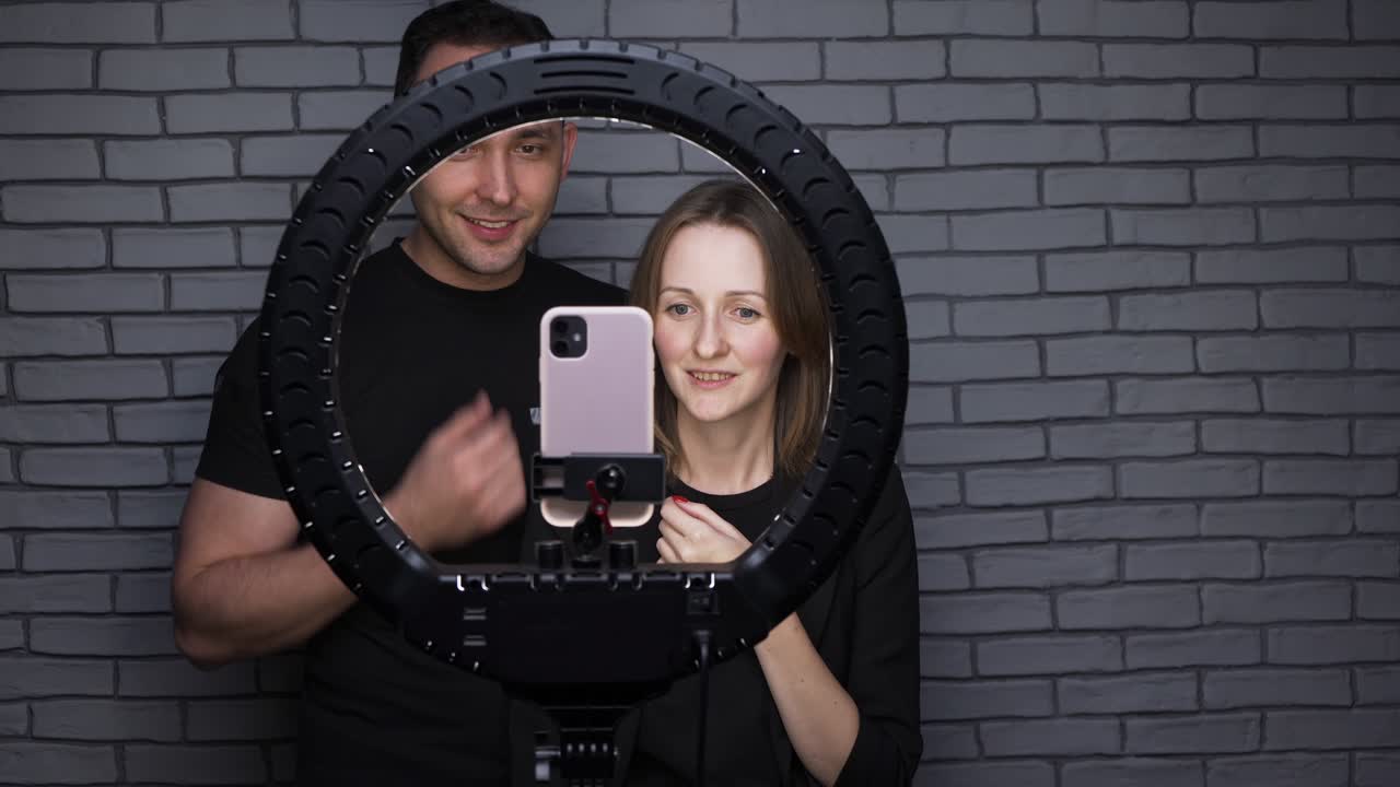 imágenes de una pareja de bloggers con una lámpara led de anillo en el fondo de la pared de ladrillo