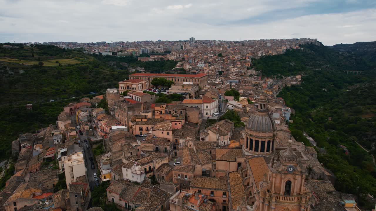 Aerial drone of Ragusa Ibla, terraced cityscape, sunlight reflecting tiled rooftops. Sicily, Italy