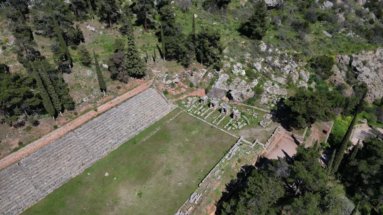 Drone descent over Delphi stadium establishing aged stone seating and surrounding forest