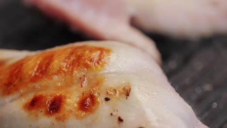 roasted rabbit legs in a grill pan, healthy diet meat close up, chef cooking rabbit on kitchen restaurant, black background. top view
