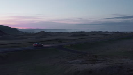 Commercial-birds-eye-drone-view-of-car-driving-on-ring-road-in-Iceland.-Birds-eye-view-car-fast-driving-on-ring-road,-the-most-important-icelandic-highway