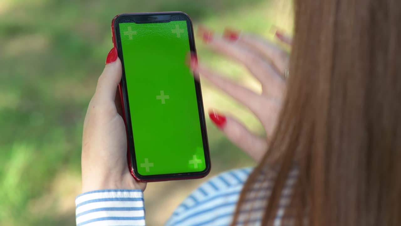 mujer tocando la pantalla verde de un teléfono móvil inteligente