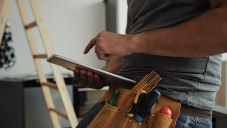 video of carpenter with tool belt scrolling digital tablet