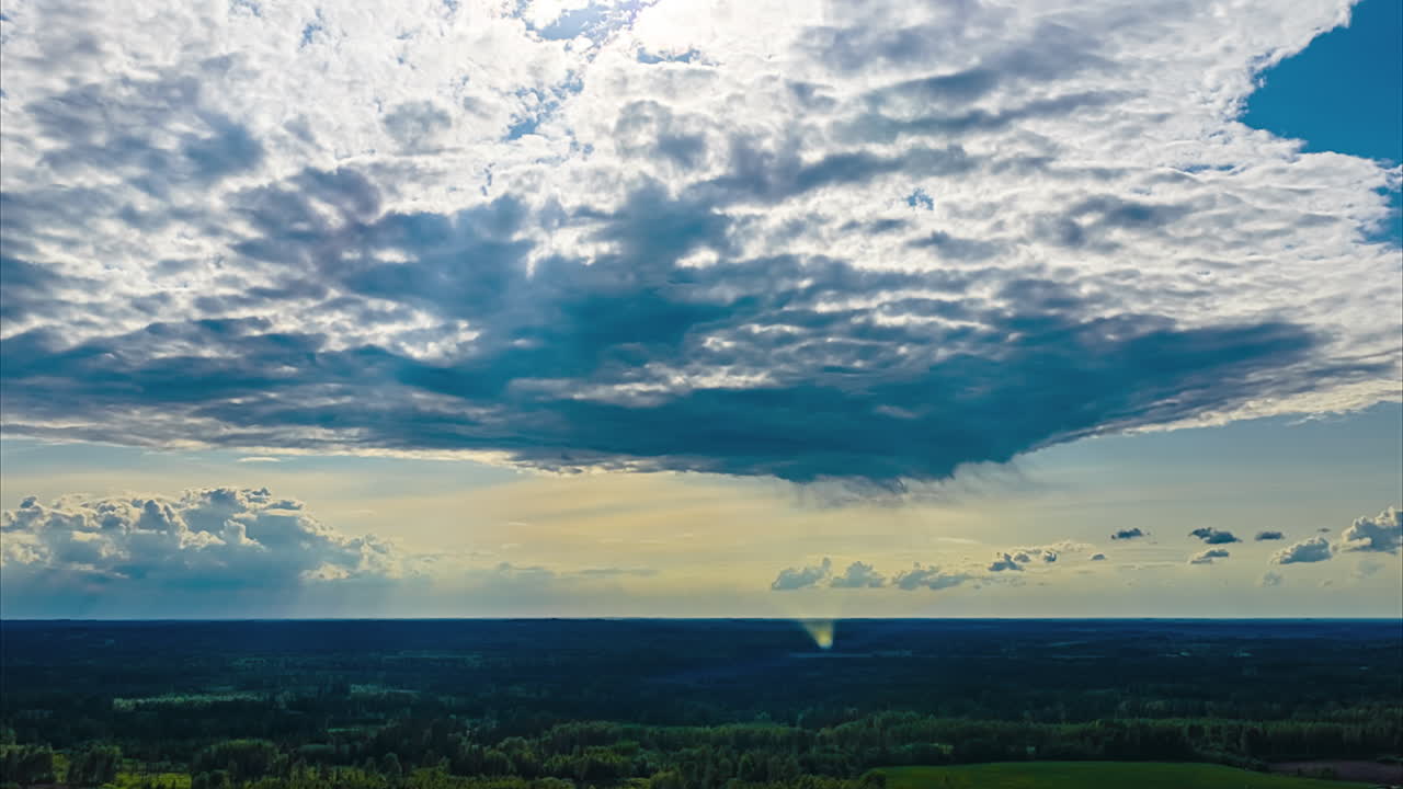 Dark rain clouds casting shadows over vast rural landscape and farms in drone hyperlapse