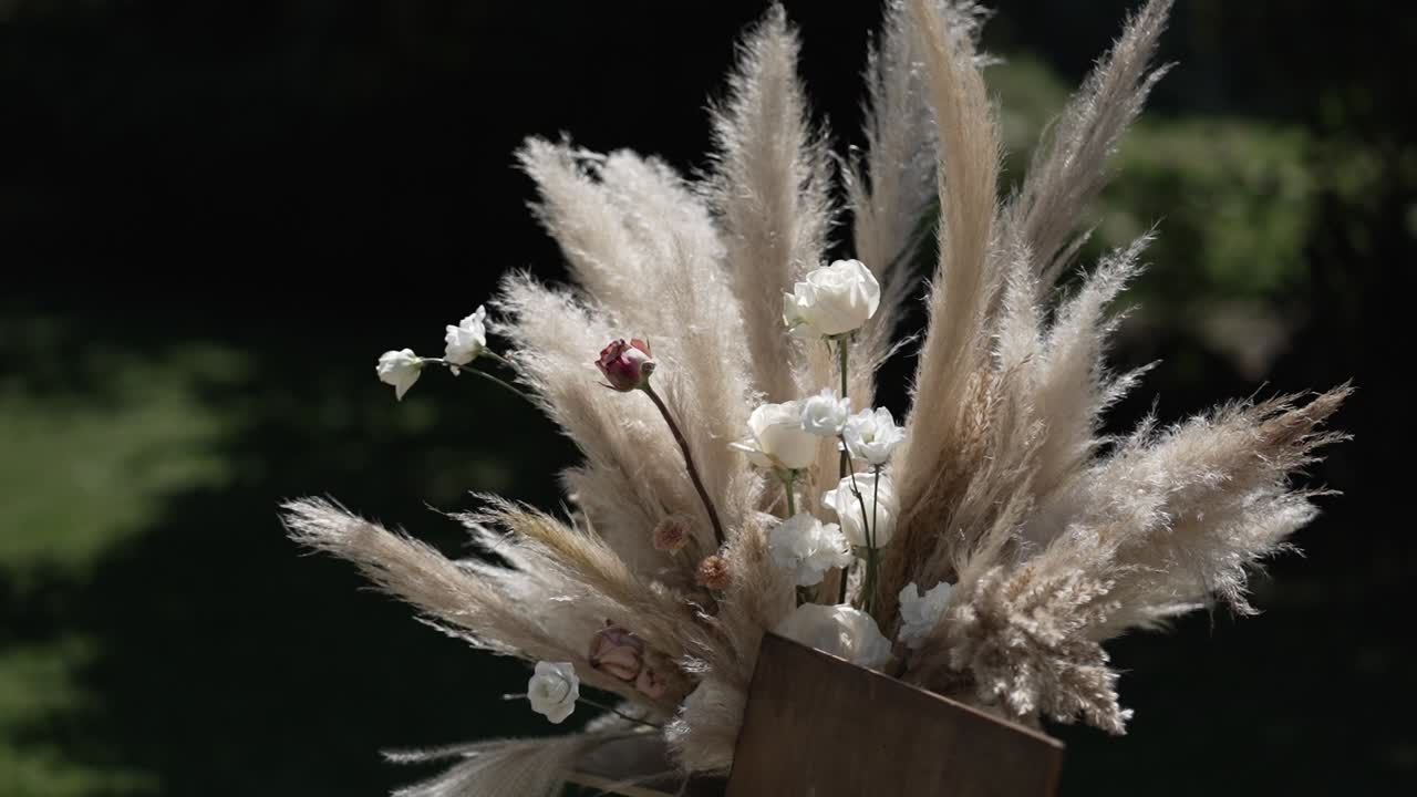 Boho wedding arrangement with pampas grass and white flowers in natural light.