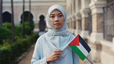 muslim woman in hijab holds palestinian flag in a display of solidarity