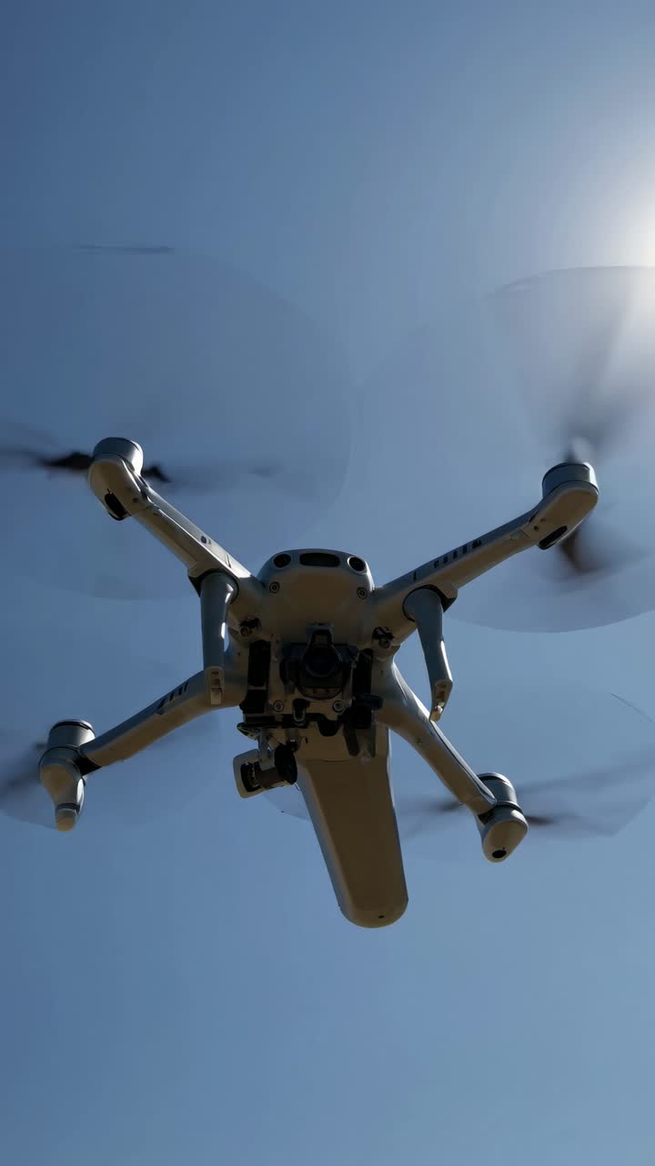 Rekaman sudut rendah drone terbang dengan latar langit biru cerah, merekam video.