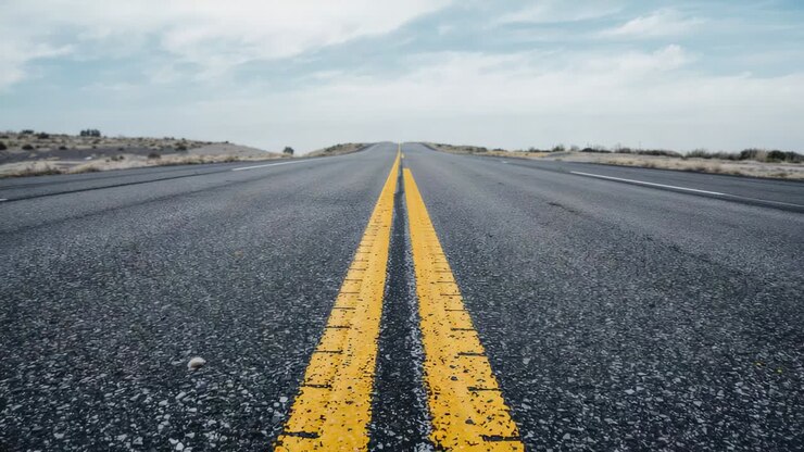 Ripresa con telecamera ad angolo basso che avanza lungo una strada nel deserto per rivelare una doppia linea gialla e schegge di vernice