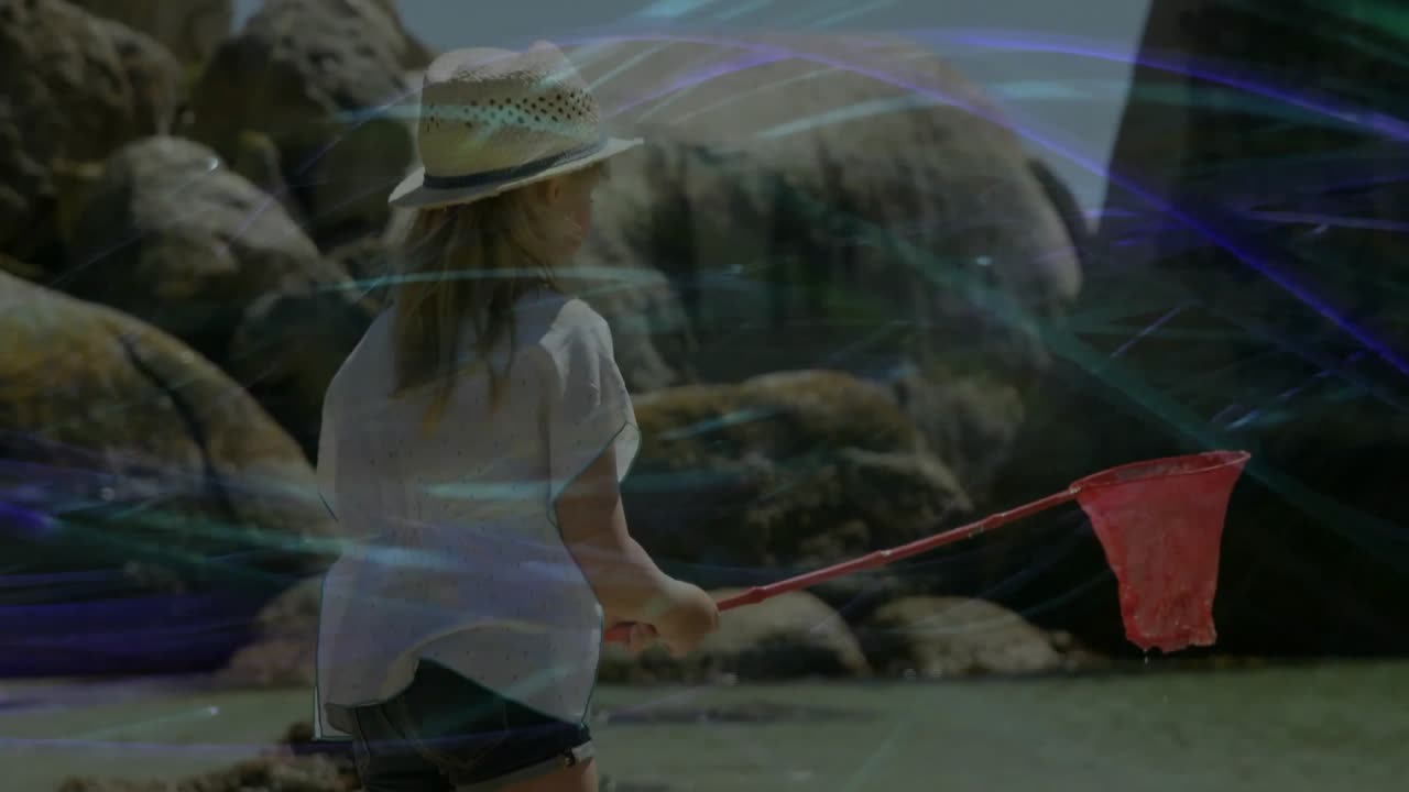 Jeune fille debout dans l'eau, abaissant un filet rouge parmi les rochers, à la recherche de petites créatures à des fins éducatives.
