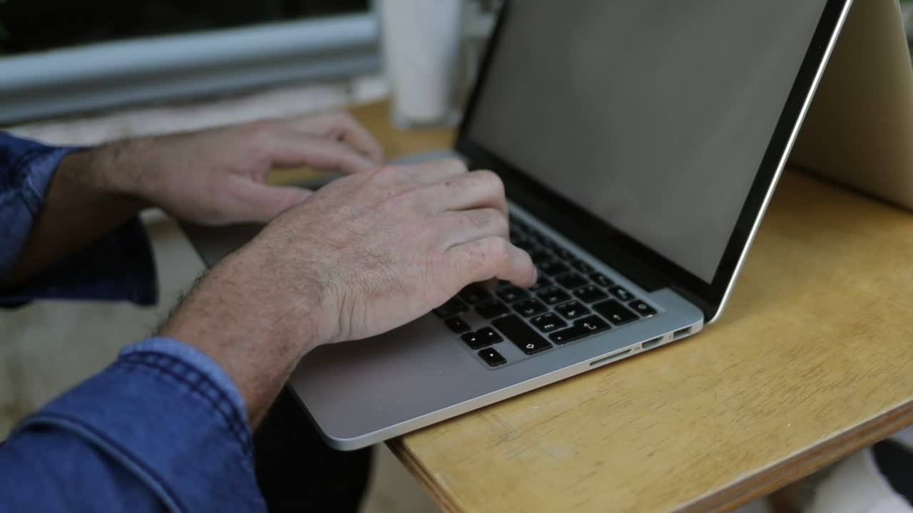 manos masculinas escribiendo en el teclado de la computadora portátil
