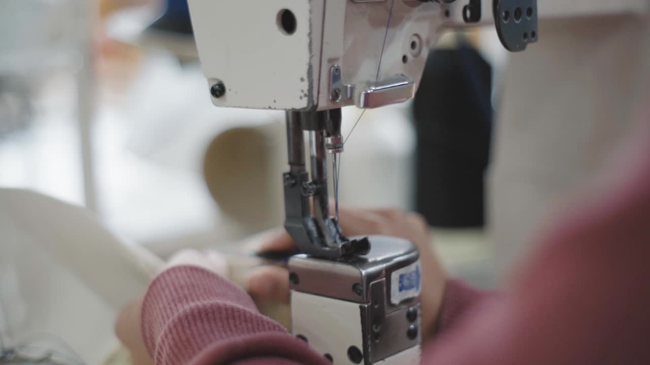 cierre de las manos de los trabajadores usando una máquina de coser industrial para coser cuero color crema