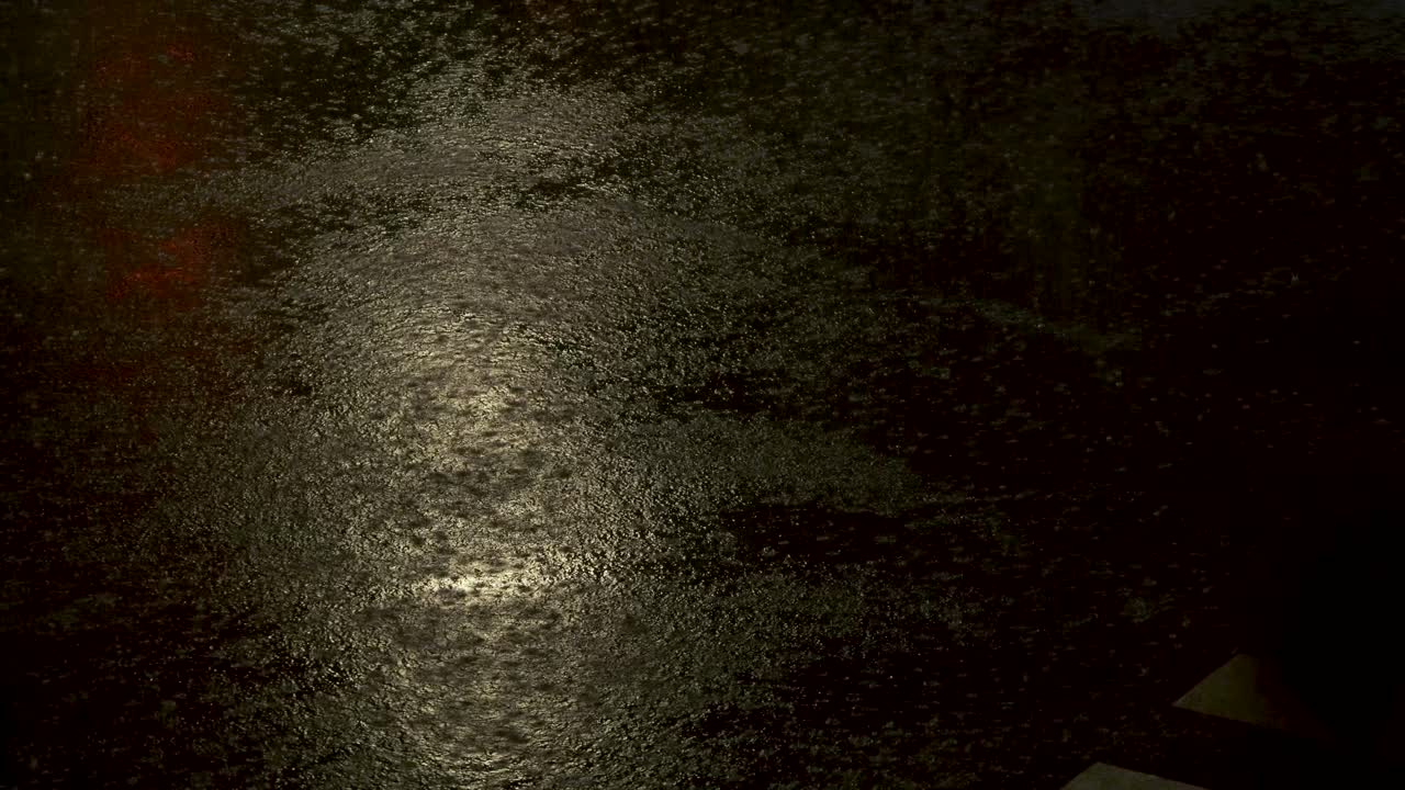 lluvia torrencial sobre el pavimento por la noche, con autos y reflejos