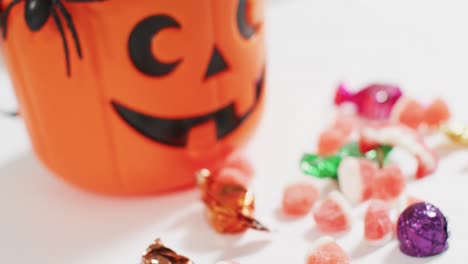 Scary-halloween-pumpkin-printed-bucket-full-of-candies-against-grey-background