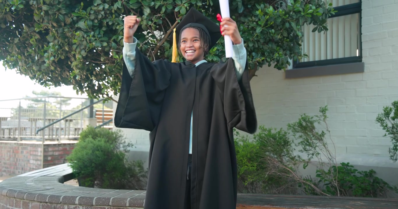 African teen male in gown holding diploma celebrating, pumping fists and tossing cap on campus