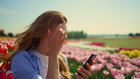 Junge-Frau-Lächelt-Im-Schönen-Garten-Zum-Mobiltelefon.-Hübsches-Mädchen,-Das-Sich-Ausdehnt.