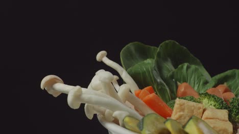 close up of a white bowl of shabu ingredients spinning around on the black background