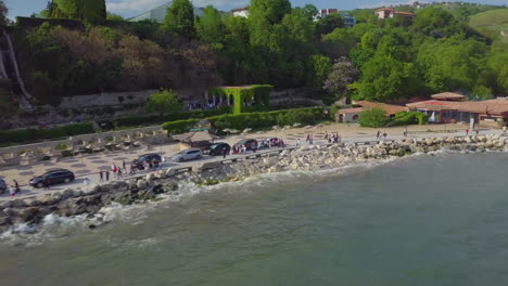 drone shot of people walking near coastline of black sea and balchik palace