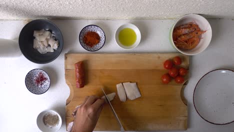 hand of male kitchen chef preparing squid on wooden cutting board, looking down view