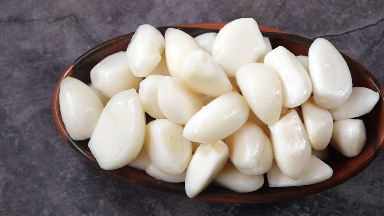 Bawang Putih Kupas dalam Mangkuk di atas Latar Belakang Gelap